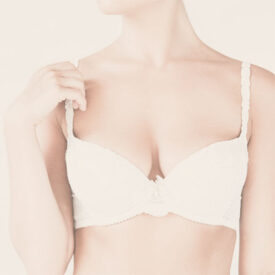 woman wearing off white bra holds strap with one hand Dr. Christine Rodgers Denver Plastic Surgery